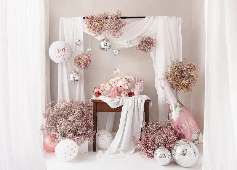 Elegant wedding decoration featuring pink flowers, Foil Balloons, and draped fabric for a bridal celebration.