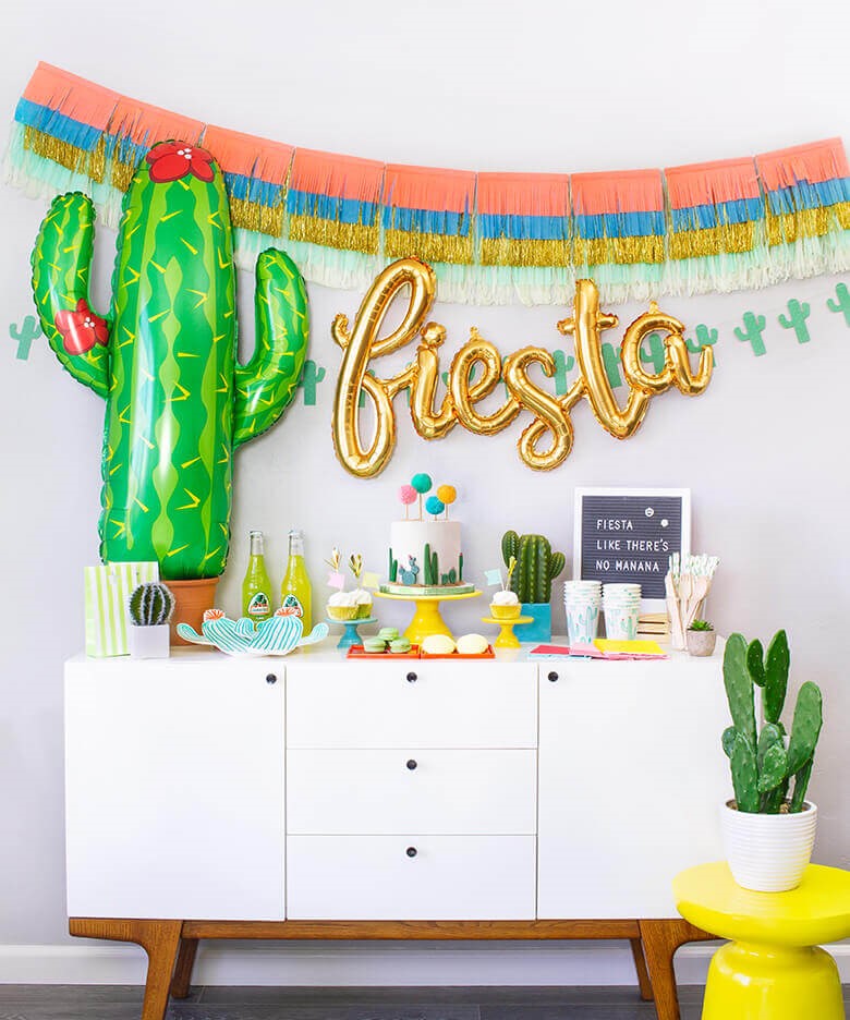Colorful fiesta party setup featuring a 104 cm foil cactus balloon, decorative elements, and vibrant tableware.