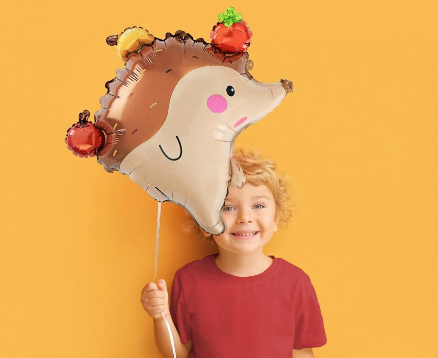 Smiling child holding a 45 cm foil balloon shaped like a hedgehog with apples, perfect for celebrations and parties.