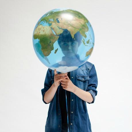 Child holding a 56 cm Planet Earth foil balloon, showcasing the globe design with blue oceans and green continents.
