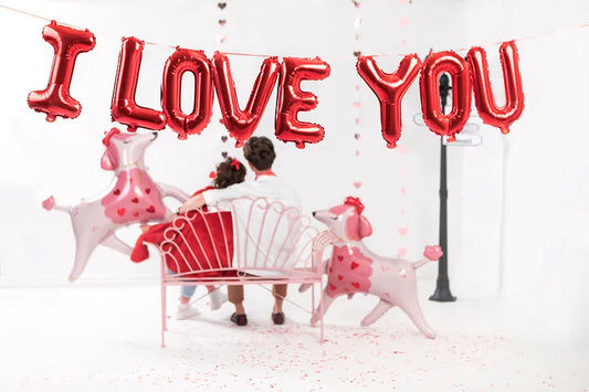 Red foil balloons spelling 'I Love You' in a festive setting with playful dog balloons, perfect for celebrations.